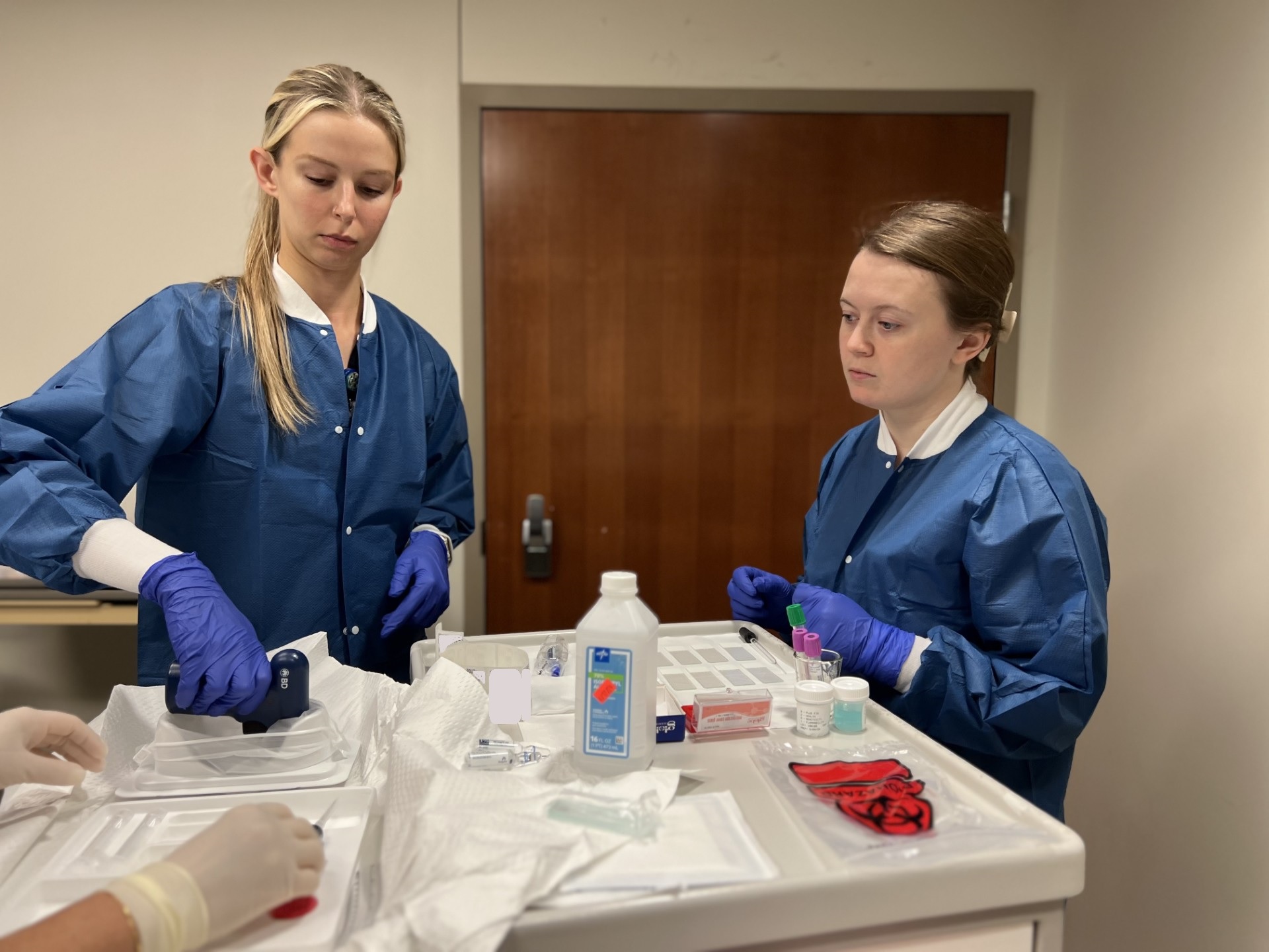 two lab workers in blue lab coats working with bone marrow samples